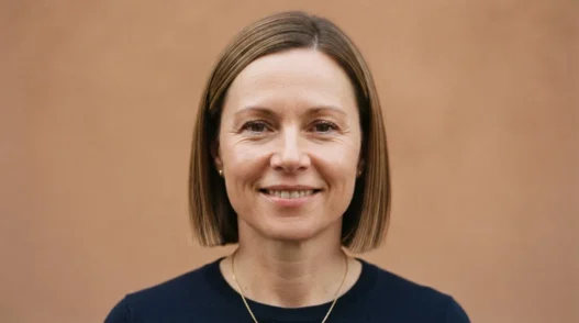 Woman with round face wearing a polished blunt bob cut ending just below the chin, editorial front view