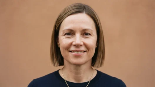 Woman with round face wearing a polished blunt bob cut ending just below the chin, editorial front view