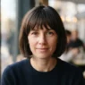 Woman with chin-length bob and soft fringe at café window seat in natural daylight