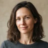 Woman with collarbone-length hair relaxed and unstyled against oat backdrop in ordinary daylight
