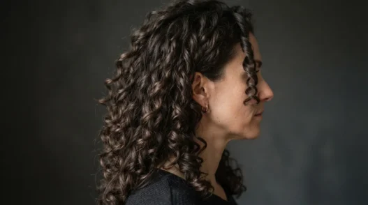 Woman with long natural curls fully air-dried and styled, viewed from the side with raking light separating each clump