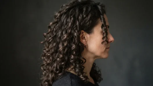 Woman with long natural curls fully air-dried and styled, viewed from the side with raking light separating each clump