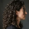Woman with long natural curls fully air-dried and styled, viewed from the side with raking light separating each clump