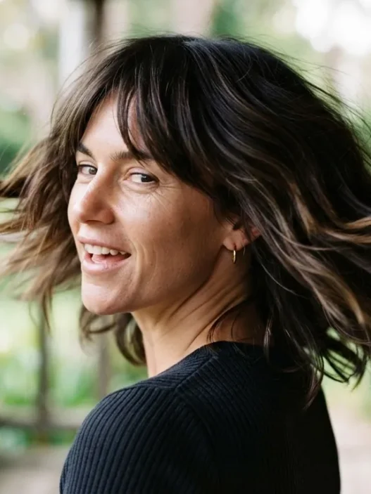 Woman with modern shoulder-length shag haircut mid-turn showing layer movement on a sunlit porch