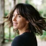 Woman with modern shoulder-length shag haircut mid-turn showing layer movement on a sunlit porch