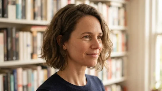 Woman with a textured bob seven weeks grown out, sitting beside a bookshelf in warm afternoon light, hair filling most of the frame
