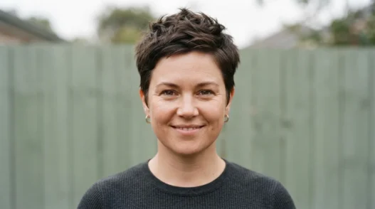 Woman with rounder face wearing textured pixie with volume at crown, photographed outdoors in soft overcast light