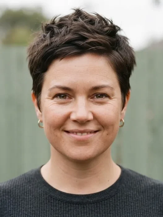 Woman with rounder face wearing textured pixie with volume at crown, photographed outdoors in soft overcast light