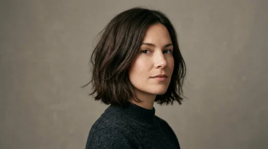 Woman with fresh chin-length textured bob in studio portrait against warm grey backdrop