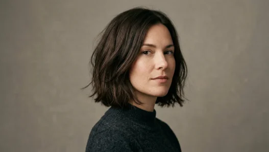 Woman with fresh chin-length textured bob in studio portrait against warm grey backdrop