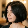 Woman with thick short chin length bob styled close to head in warm salon